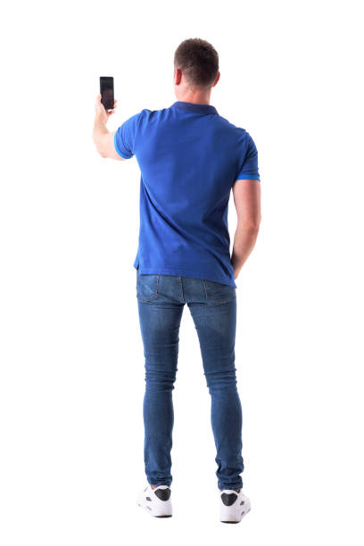 Rear view of modern adult casual man taking photo with smart phone. stock photo