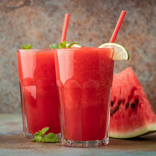 istock Watermelon slushie with lime, summer refreshing drink in tall glasses on a blue rusty background 1017891038