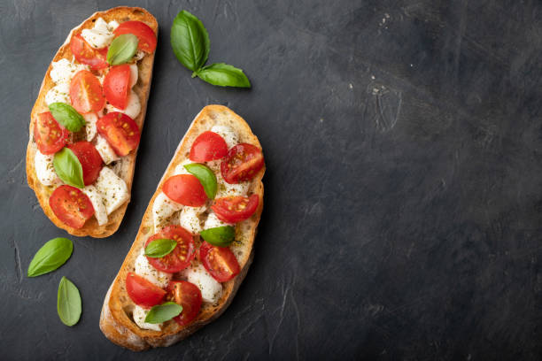 istock Bruschetta with tomatoes, mozzarella cheese and basil on a black background. Traditional italian appetizer or snack, antipasto. Top view with copy space. Flat lay 1017891062