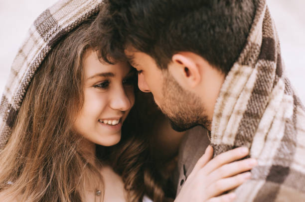 istock happy young beautiful couple hugging under blanket 1017898658