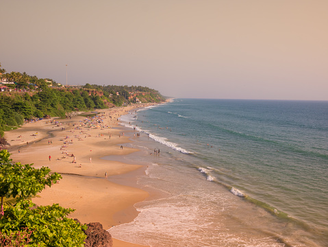 Beautiful and relaxing beach flanked by green palm trees at sunset. Varkala, Kerala, India