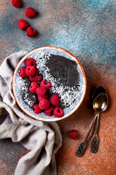 istock Activated charcoal smoothie and chia seed pudding bowl, vegan detox dessert with raspberry and coconut milk. Overhead, top view, flat lay 1017904964