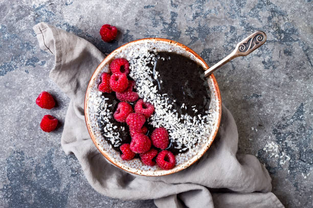 istock Activated charcoal smoothie and chia seed pudding bowl, vegan detox dessert with raspberry and coconut milk. Overhead, top view, flat lay 1017905866