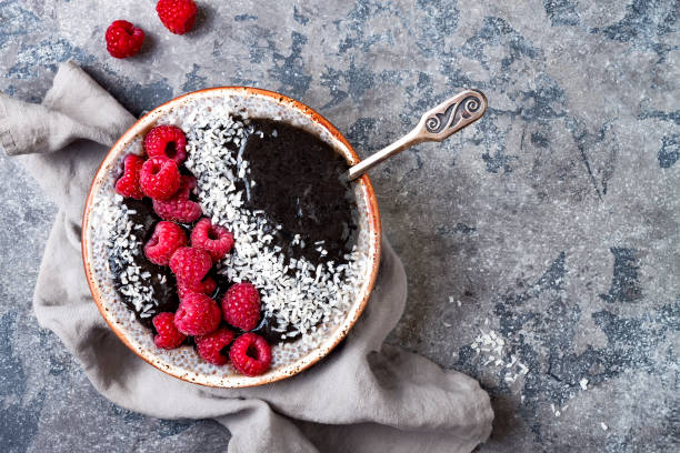 istock Activated charcoal smoothie and chia seed pudding bowl, vegan detox dessert with raspberry and coconut milk. Overhead, top view, flat lay 1017905906