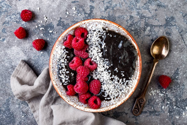 istock Activated charcoal smoothie and chia seed pudding bowl, vegan detox dessert with raspberry and coconut milk. Overhead, top view, flat lay 1017905926