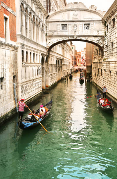 View of bridge of sighs with gondoliers carrying tourists in their gondolas in Venice, italy at sunset Venice, Italy, Jun 8, 2018: View of bridge of sighs with gondoliers carrying tourists in their gondolas in Venice, italy at sunset gondola traditional boat photos stock pictures, royalty-free photos & images