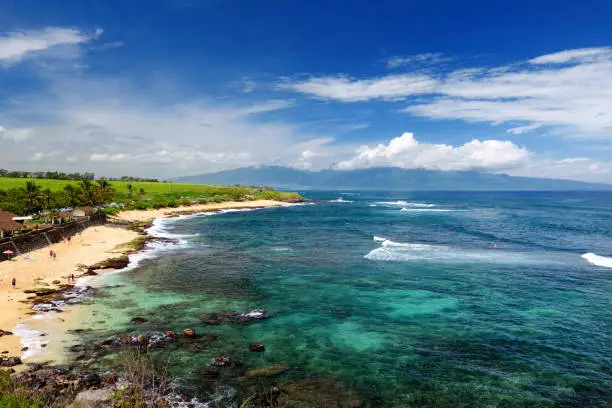 Photo of Famous Hookipa beach, popular surfing spot filled with a white sand beach, picnic areas and pavilions. Maui, Hawaii.