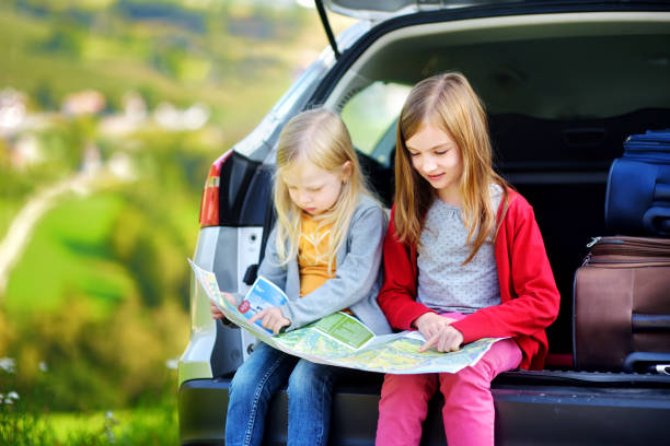 Two adorable little sisters exploring a map before going on vacations with their parents