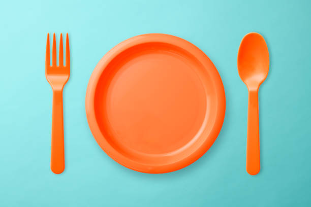 istock Orange plastic plate, Folk, and spoon on blue background 1017981476