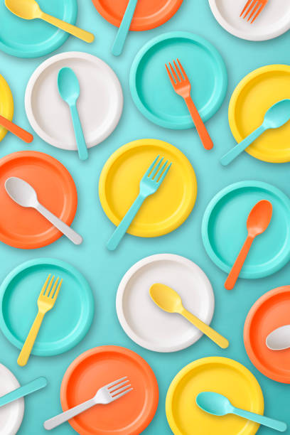 Lots of multi colored plastic tableware on blue background Overhead shot of multi colored plastic tableware on blue background. vibrant color lifestyles vertical close up stock pictures, royalty-free photos & images