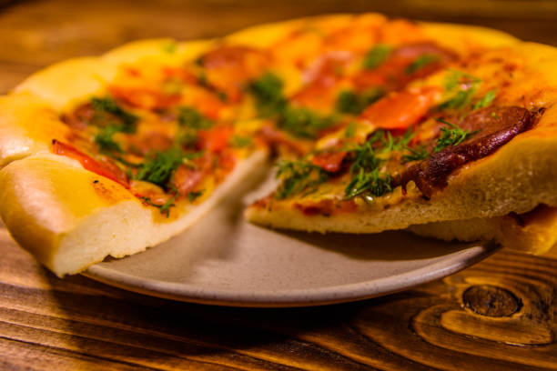 istock Ceramic plate with sliced homemade pizza on a wooden table 1018006816