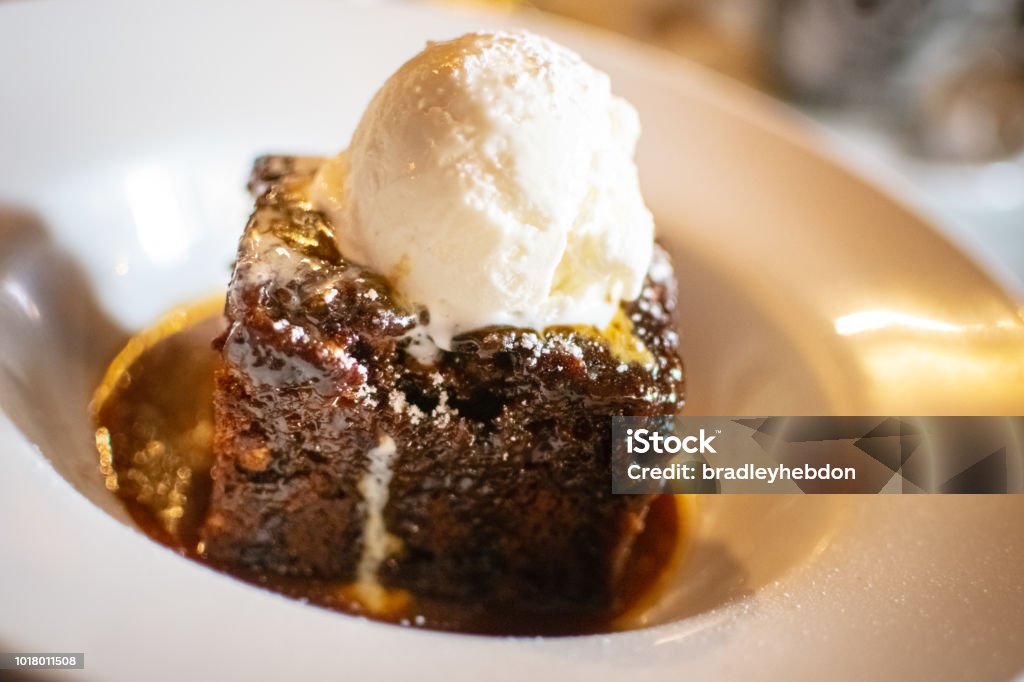 Sticky toffee pudding served with ice-cream Sticky toffee pudding is a British dessert consisting of a very moist sponge cake, made with finely chopped dates, covered in a toffee sauce and often served with a vanilla custard or vanilla ice-cream Mousse - Dessert Stock Photo