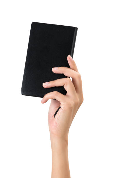 istock Woman hand holding a black diary, isolated on white background. 1018011854