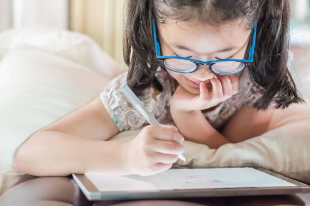 istock Asian school child girl using smart tablet device digital technology drawing on innovative touchscreen surface 1018022330