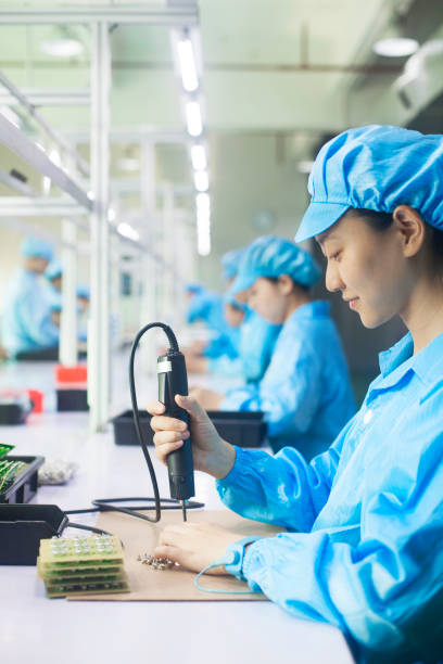 lavoratori in uniforme in una fabbrica di illuminazione a led a dongguan, cina - chinese production foto e immagini stock