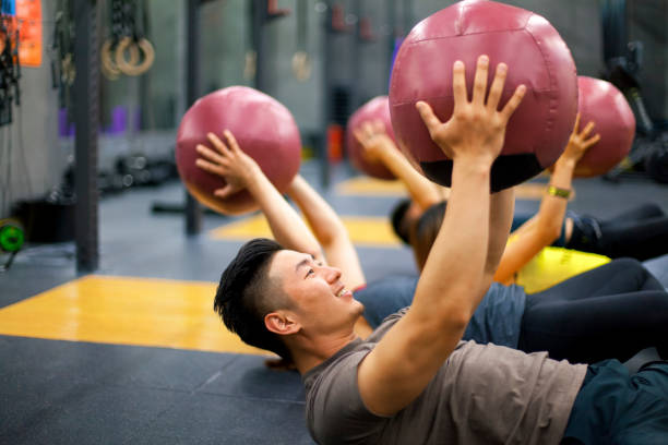 junge menschen heben gymnastikball in übung - anaerobic stock-fotos und bilder