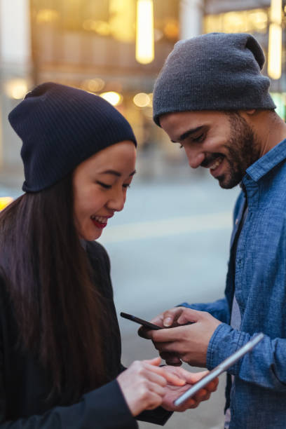 istock Young couple chatting, using smartphone on city street 1018047450