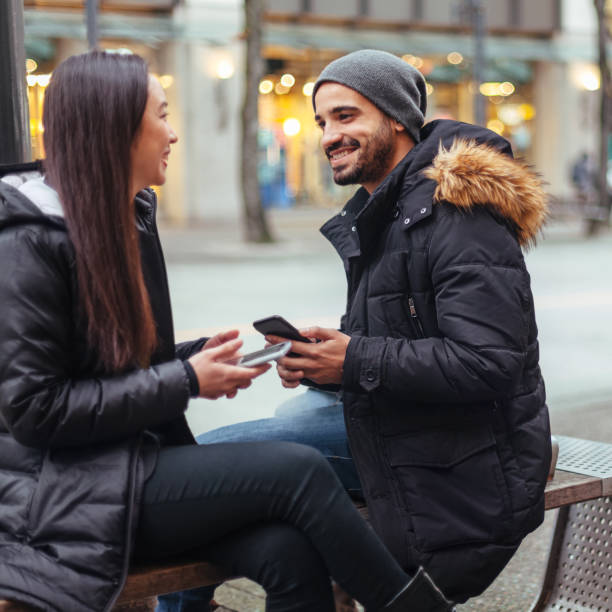 istock Young couple chatting, using smartphone on city street 1018047508