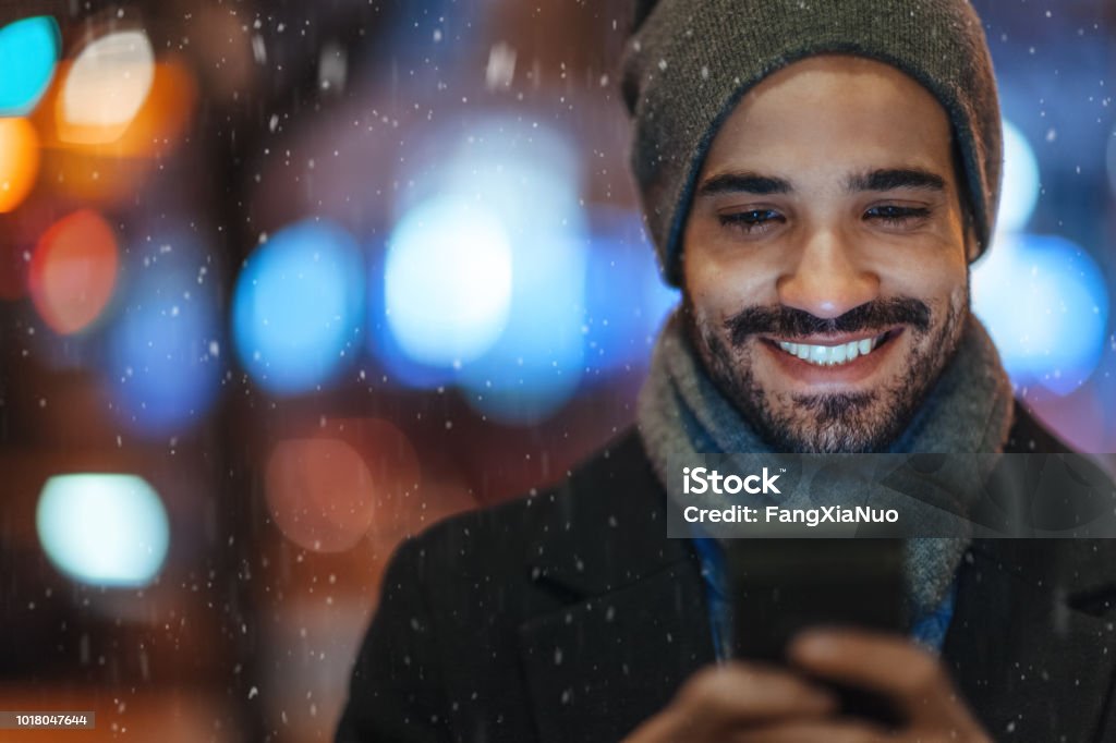 Junger Mann mit Smartphone auf Stadtstraße an einem verschneiten Tag - Lizenzfrei Männer Stock-Foto