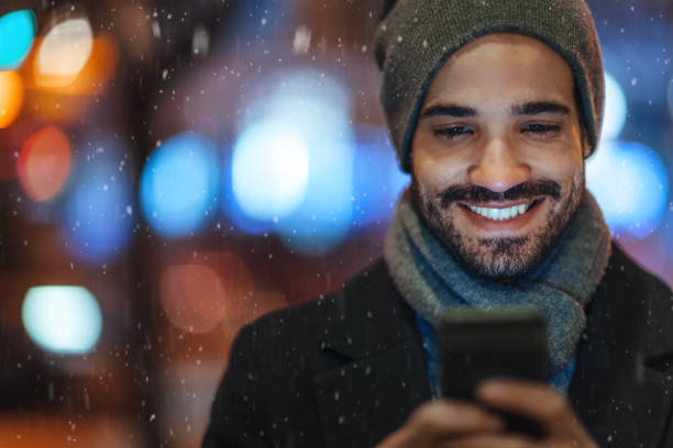 Young man using smartphone on city street on a snowy day Young man using smartphone on city street on a snowy day vancouver canada photos stock pictures, royalty-free photos & images