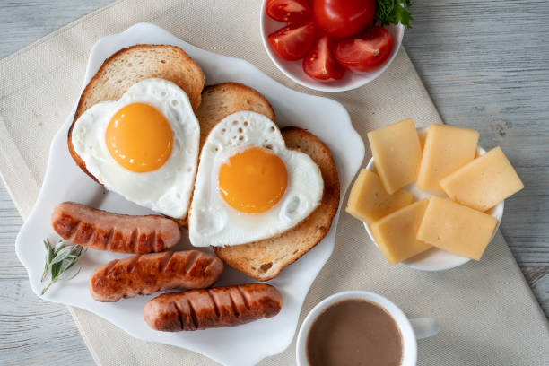 Breakfast with love - fried eggs in the shape of a heart, fried sausages and coffee stock photo