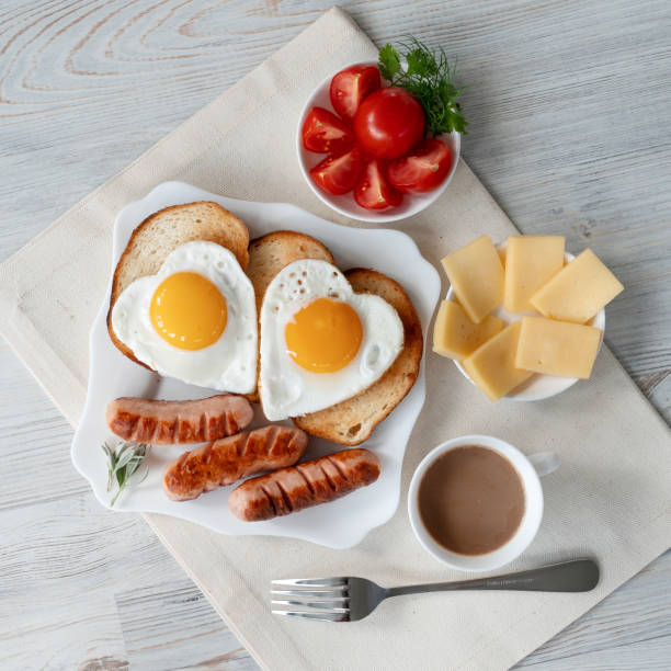 Breakfast with love - fried eggs in the shape of a heart, fried sausages and coffee stock photo
