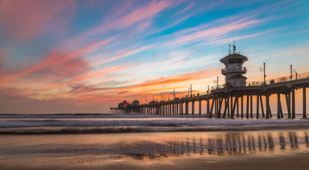 increíbles colores del atardecer por el muelle de huntington beach, en la ciudad famosa de surf en california - embarcadero fotografías e imágenes de stock