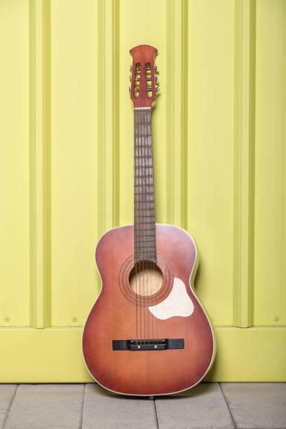 istock Classical guitar against yellow metal wall. Music concept. 1018082104