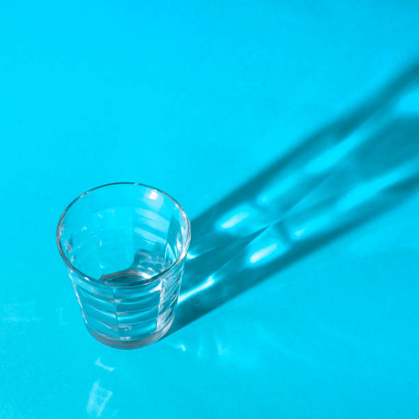 istock Transparent glass Cup on blue background and long shadow from it with different pictures 1018082208