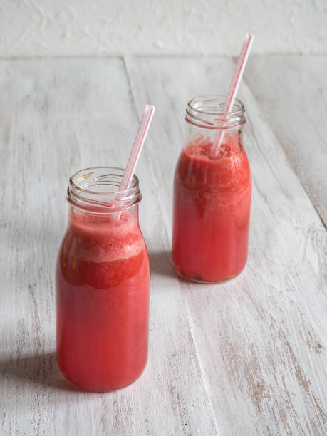 istock Pink fruit smoothie on a white wooden table. 1018082546