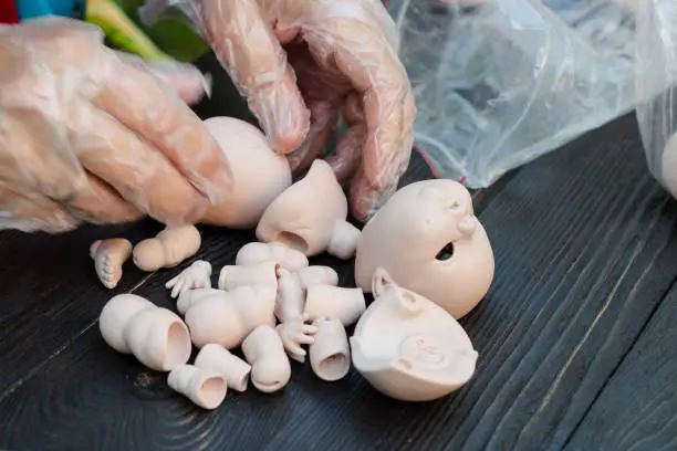 Photo of Female hands make dolls of BJD in the workplace. Processing the workpiece. The concept of the craft of the master manufacturer of dolls. Selective focus.