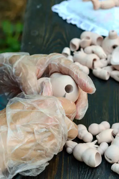 Photo of Female hands make dolls of BJD or reborn in the workplace. Processing the workpiece. The concept of the craft of the master manufacturer of dolls. Selective focus. Vertical.