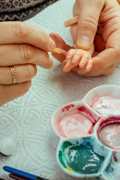 Photo of Female hands make dolls of BJD or reborn in the workplace. Processing the workpiece. The concept of the craft of the master manufacturer of dolls. Selective focus. Vertical.