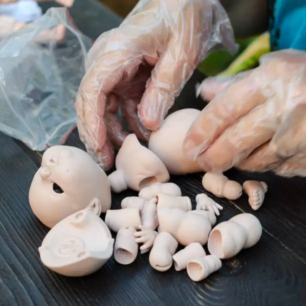 Photo of Female hands make dolls of BJD in the workplace. Processing the workpiece. The concept of the craft of the master manufacturer of dolls. Selective focus. For instagram format. Square.