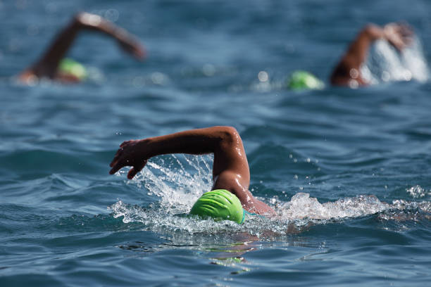 tres bañistas nadan en el océano - triathlon fotografías e imágenes de stock