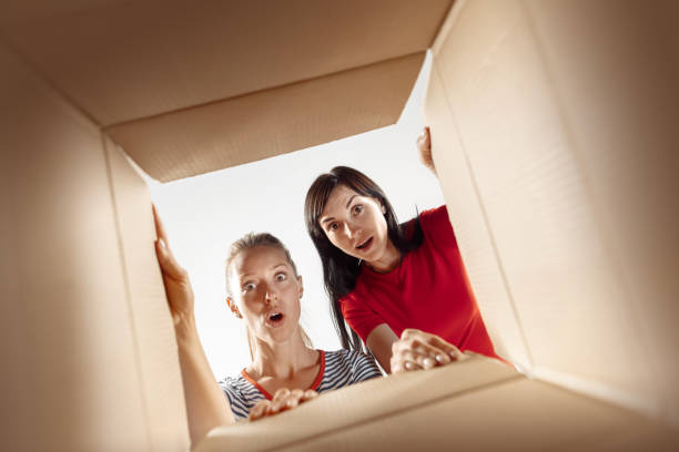 istock Women unpacking and opening carton box and looking inside 1018106326