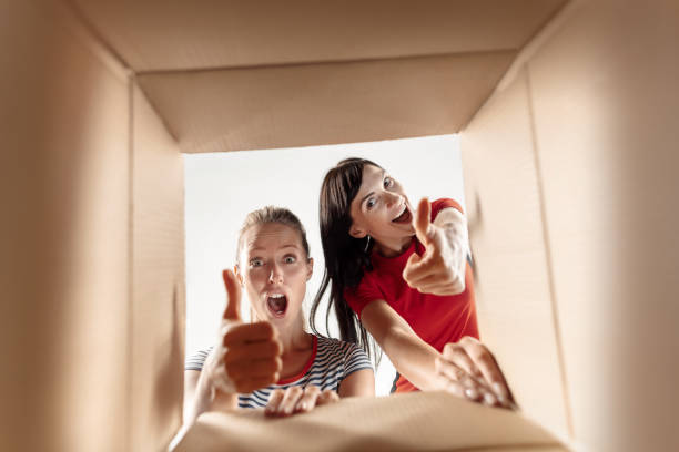 istock Women unpacking and opening carton box and looking inside 1018106418