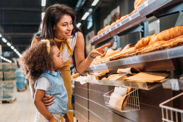 食料雑貨品店の娘を菓子で指で指しているアフリカ系アメリカ人の女性 - preschooler child offspring purity ストックフォトと画像