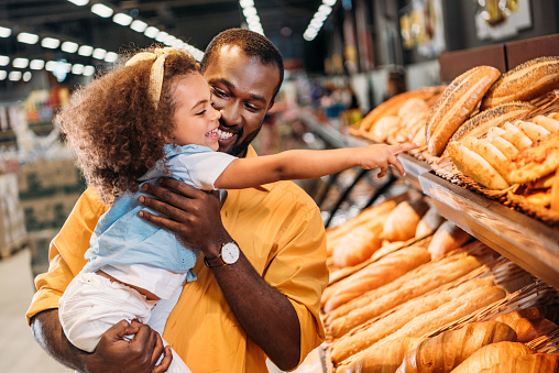 african american little child pointing by finger at pastry to father in supermarket