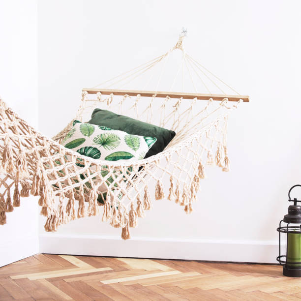 istock Sunny and bright bedroom with natural string hammock, plants and shelves with accessories. Modern bedroom with brown wooden parquet. 1018117800