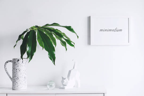 istock Minimalistic concept of white home interior whit copy space, tropical leaf and cat figures. Scandinavian white cupboard concept. 1018121372