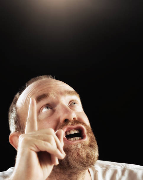 Mature man looks heavenwards, worried and wagging finger A worried-looking mature bearded man looks up towards heaven, wagging his finger and perhaps arguing with God. man with a light bulb over his head stock pictures, royalty-free photos & images
