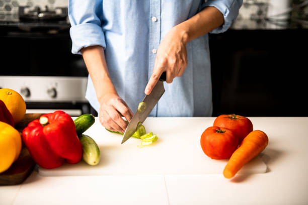 istock Woman chopping cucumber in kitchen. 1018134394