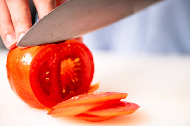 istock Woman chopping tomato in kitchen. 1018134440