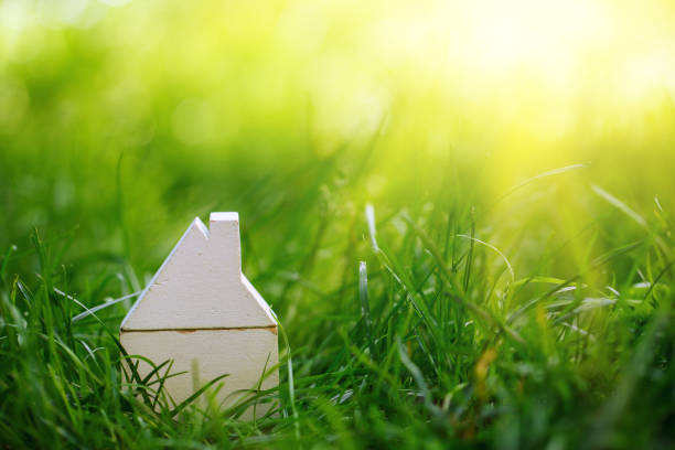 istock Small model wooden white house over green grass background 1018137836