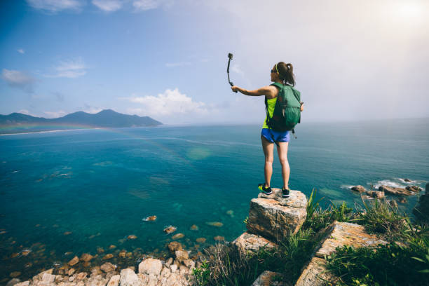 femme de randonnée en bord de mer en prenant un selfie - travel beach mountain pacific ocean photos et images de collection