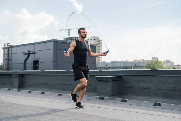 istock handsome sportsman training with jumping rope on roof 1018139368