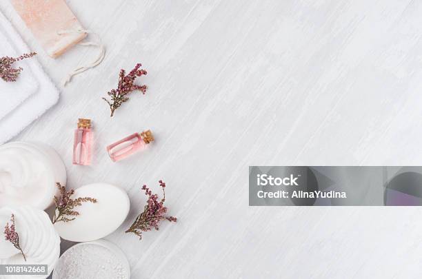 Organic Homemade White Cosmetics Set With Pink Flowers And Massage Oil On White Wooden Board Top View Border Stock Photo - Download Image Now