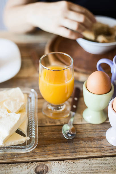 Breakfast - boiled eggs with fruit juice and cow cheese at dining table, close-up, selective focus