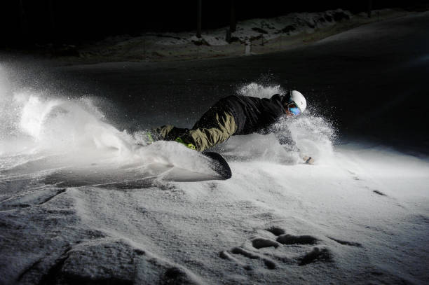 istock Active snowboarder riding down the snowy mountain slope at night 1018146236